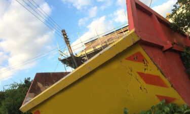 Yellow Skip Hire Container Outside A House Undergoing Roof Renovation